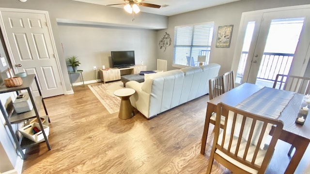 living room with a ceiling fan, light wood-style flooring, and baseboards