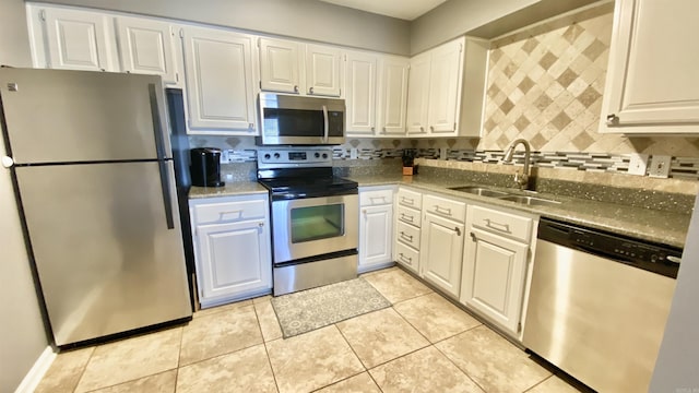 kitchen with stainless steel appliances, white cabinets, a sink, and backsplash