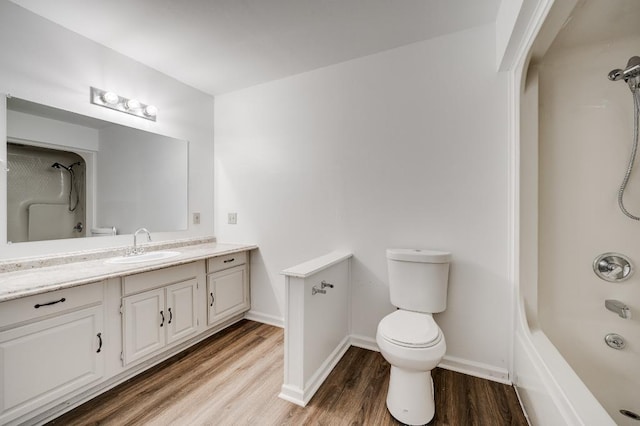 bathroom with baseboards, toilet, wood finished floors, bathtub / shower combination, and vanity