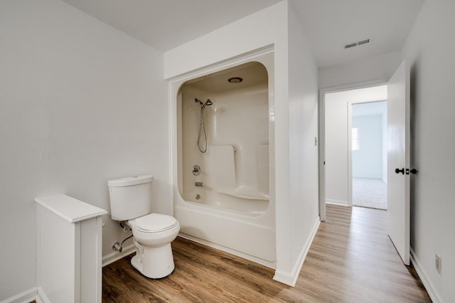 full bathroom with toilet, wood finished floors, bathing tub / shower combination, visible vents, and baseboards