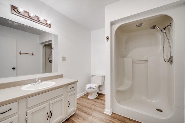 full bathroom featuring toilet, walk in shower, wood finished floors, and vanity