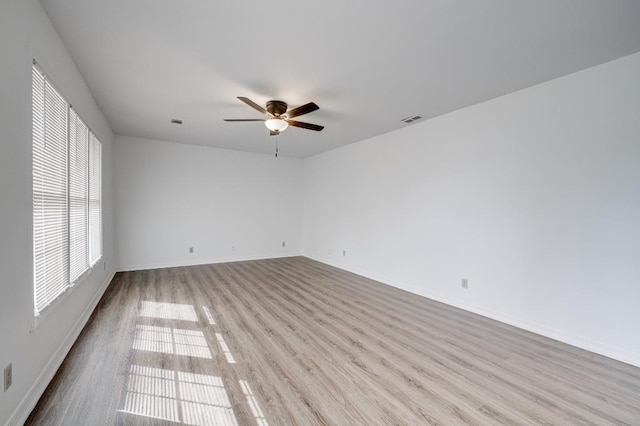 spare room featuring visible vents, ceiling fan, baseboards, and wood finished floors