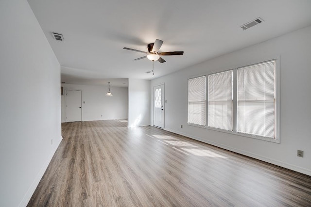 unfurnished living room with baseboards, ceiling fan, visible vents, and wood finished floors