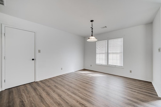 unfurnished room featuring visible vents, baseboards, and wood finished floors