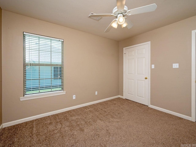 carpeted empty room featuring ceiling fan and baseboards