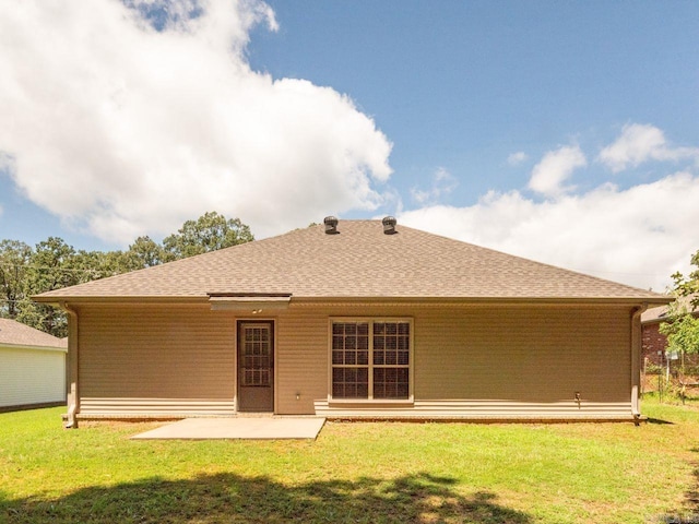 back of house featuring a shingled roof, a lawn, and a patio