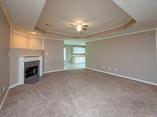 unfurnished living room featuring carpet, visible vents, ornamental molding, a tray ceiling, and a tiled fireplace