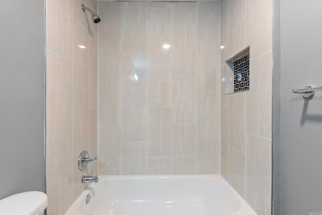 full bath with toilet, a textured wall, and shower / bathing tub combination