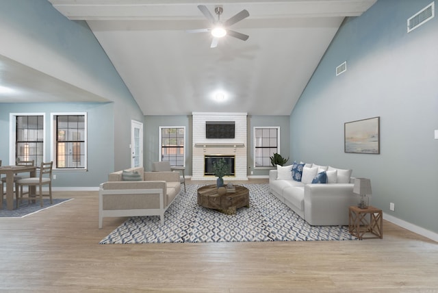 living area with visible vents, a fireplace, baseboards, and wood finished floors