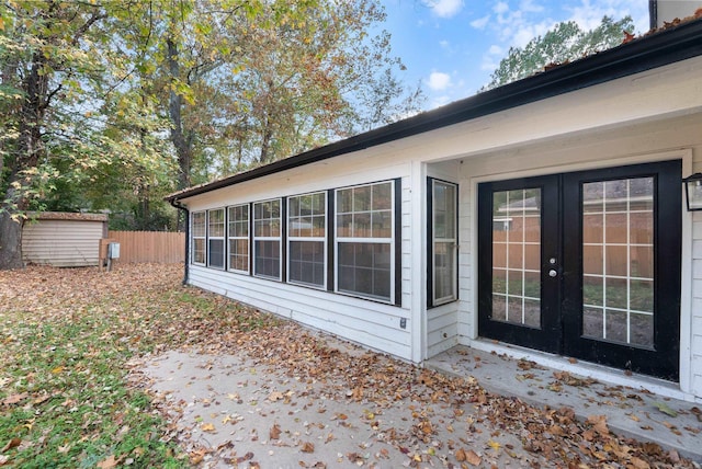 exterior space featuring french doors, fence, an outdoor structure, and a shed