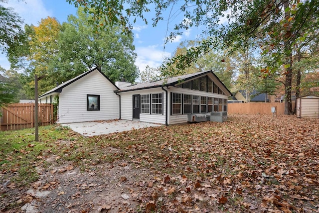 back of house featuring a shed, a chimney, a patio area, and a fenced backyard