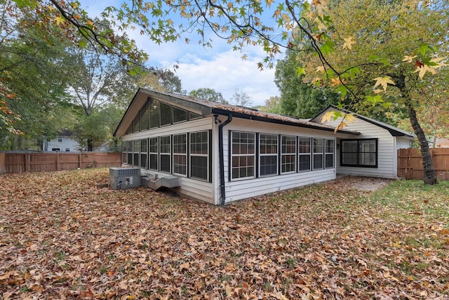 rear view of property with fence, a sunroom, and central air condition unit