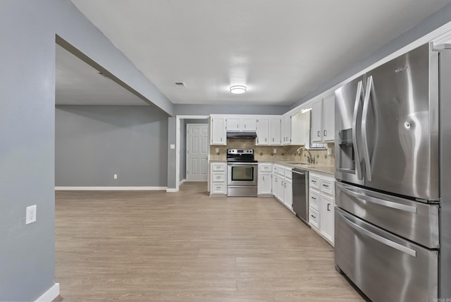 kitchen with tasteful backsplash, appliances with stainless steel finishes, white cabinetry, a sink, and under cabinet range hood