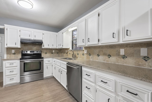 kitchen featuring light stone counters, under cabinet range hood, stainless steel appliances, a sink, and white cabinetry