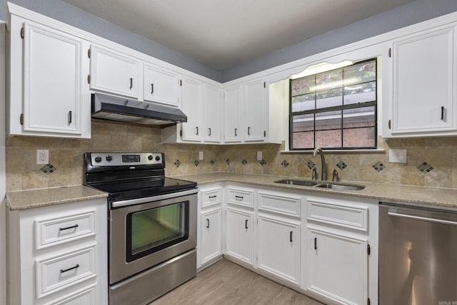 kitchen with white cabinets, appliances with stainless steel finishes, light countertops, under cabinet range hood, and a sink