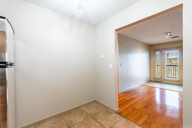 interior space with a textured ceiling, light tile patterned flooring, and baseboards