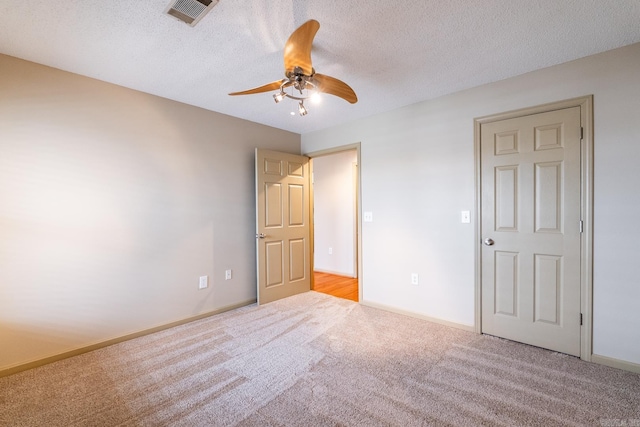 unfurnished bedroom with a textured ceiling, carpet, visible vents, and baseboards