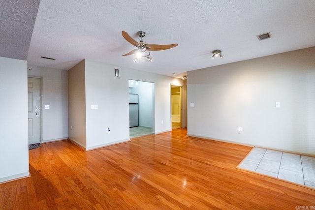 empty room featuring a ceiling fan, visible vents, and wood finished floors