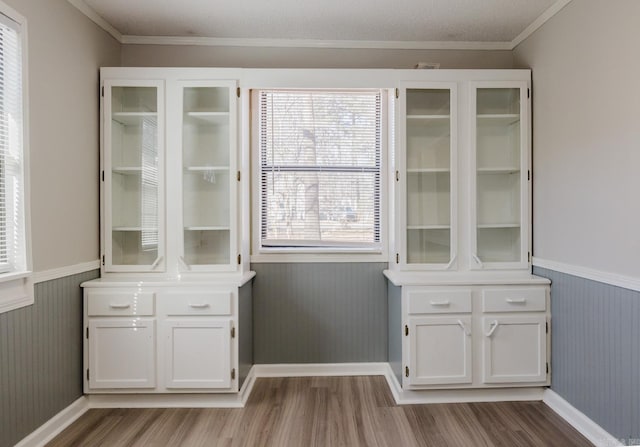 bar featuring wood finished floors, wainscoting, and ornamental molding