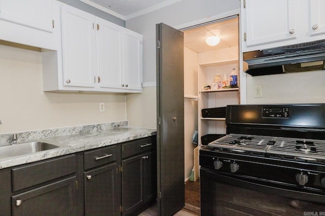 kitchen featuring under cabinet range hood, black gas range, light countertops, white cabinets, and a sink