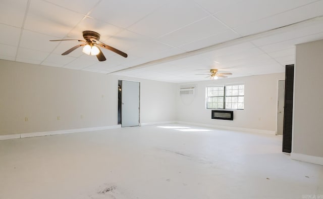 unfurnished room featuring a wall mounted air conditioner, a ceiling fan, a paneled ceiling, baseboards, and concrete flooring