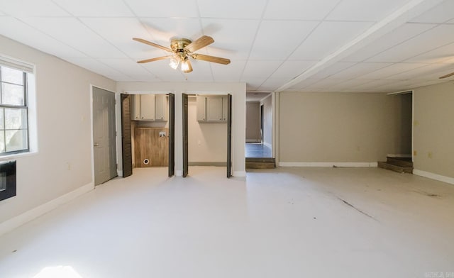 interior space featuring a ceiling fan, a paneled ceiling, baseboards, and finished concrete floors