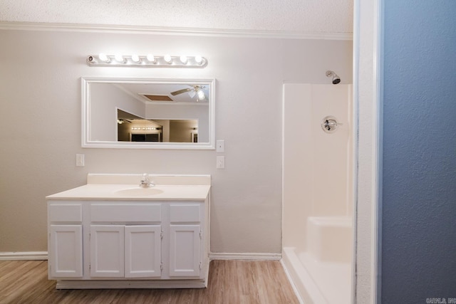 bathroom with ornamental molding, a textured ceiling, wood finished floors, a shower, and vanity