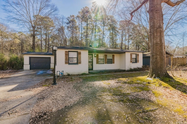 view of front of home with brick siding, concrete driveway, an attached garage, and fence