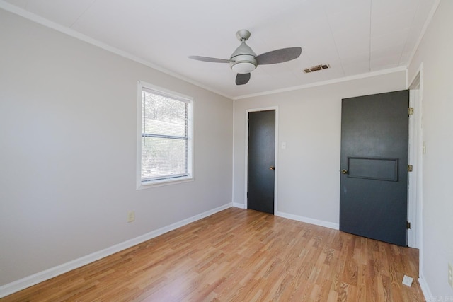 unfurnished bedroom featuring a ceiling fan, baseboards, visible vents, light wood finished floors, and crown molding