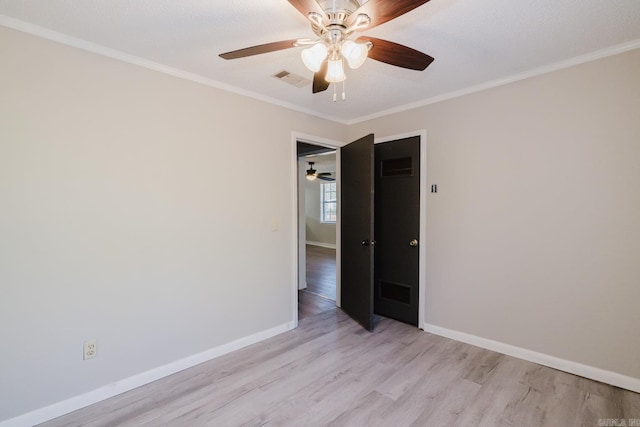 spare room with visible vents, baseboards, light wood-style floors, and ornamental molding