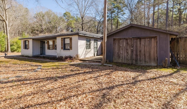 exterior space featuring a garage, an outbuilding, brick siding, and fence