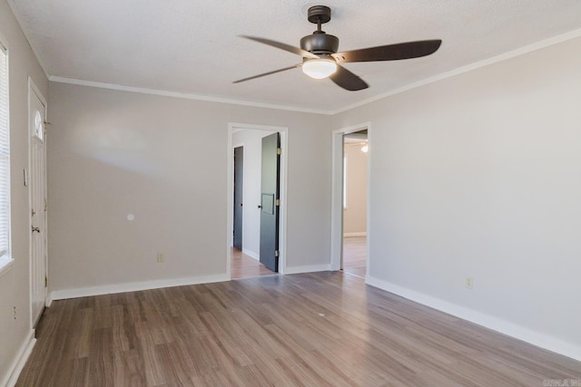 empty room featuring baseboards, a ceiling fan, wood finished floors, and crown molding