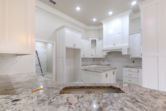 kitchen featuring light stone countertops, recessed lighting, white cabinets, ornamental molding, and decorative backsplash