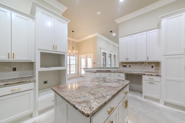 kitchen featuring a center island, light stone countertops, an inviting chandelier, crown molding, and white cabinetry