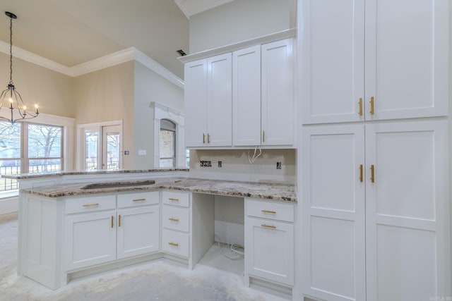 kitchen featuring white cabinets, ornamental molding, a peninsula, an inviting chandelier, and light stone countertops