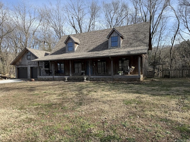 view of front facade with a porch, a shingled roof, and a front lawn