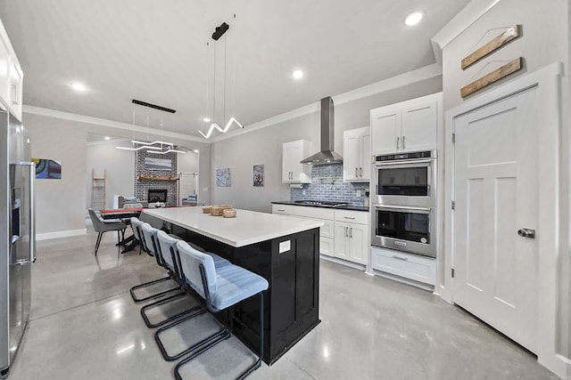 kitchen with finished concrete flooring, stainless steel appliances, wall chimney range hood, and tasteful backsplash