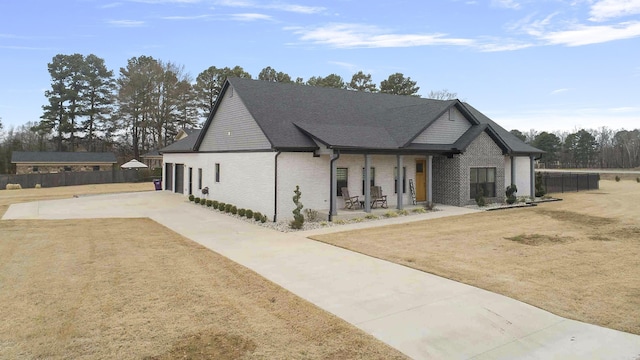 exterior space with driveway, covered porch, fence, and brick siding