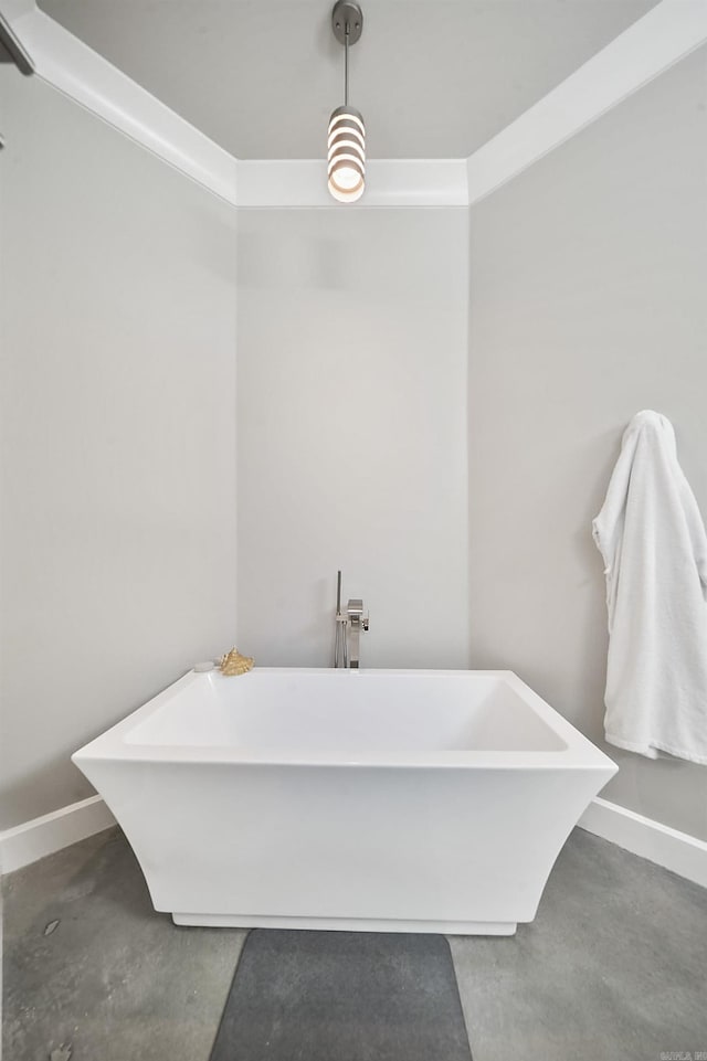 bathroom with a freestanding bath, baseboards, and concrete flooring