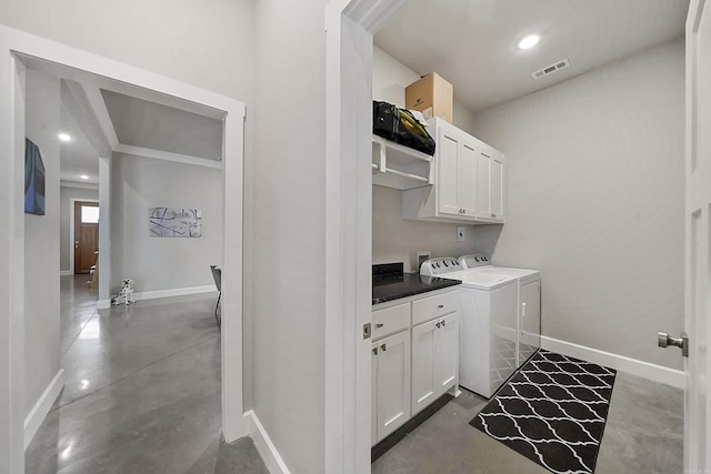 washroom featuring independent washer and dryer, visible vents, cabinet space, and baseboards