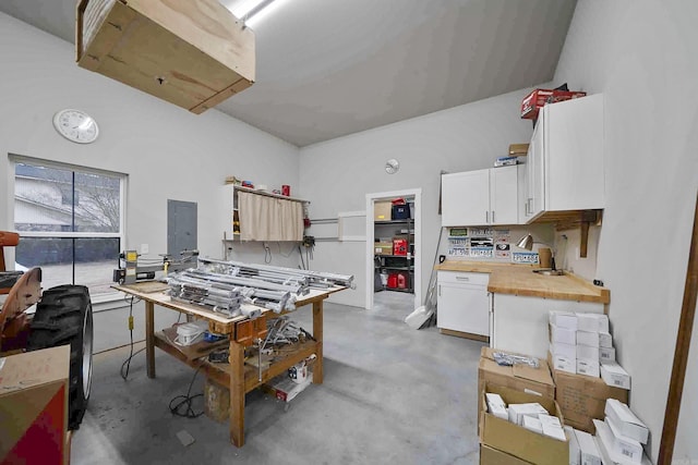 kitchen with electric panel, white cabinets, butcher block countertops, concrete floors, and open shelves