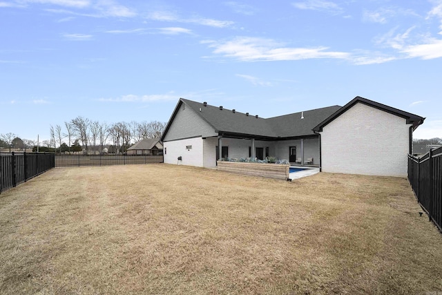 rear view of house with a yard, a fenced backyard, brick siding, and a patio