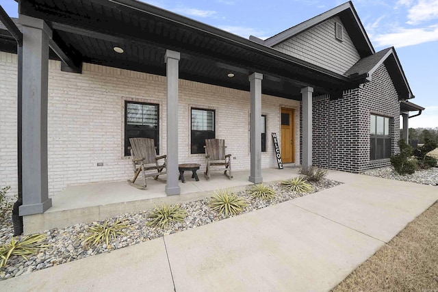 back of property with covered porch and brick siding