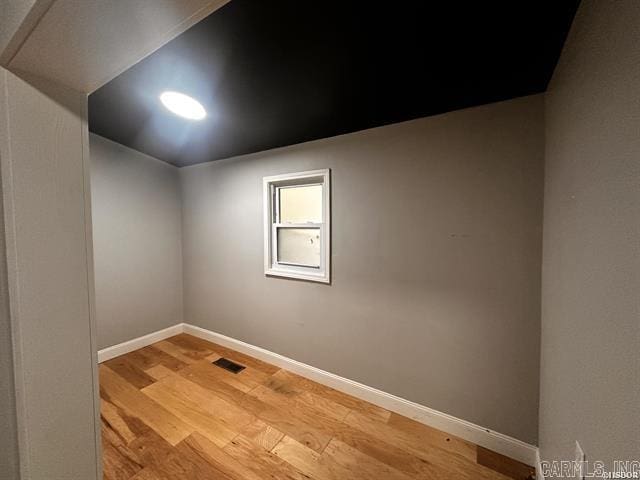 empty room featuring light wood-type flooring, visible vents, and baseboards