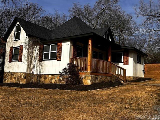 view of front of home with covered porch, a front lawn, and a shingled roof