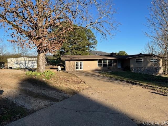 single story home featuring concrete driveway and french doors