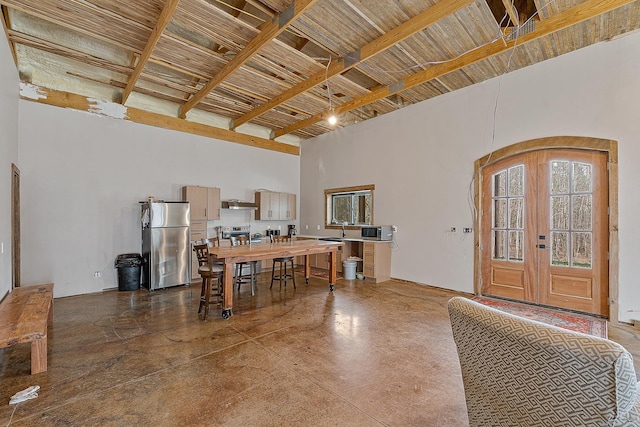 interior space featuring concrete flooring, arched walkways, french doors, and a towering ceiling