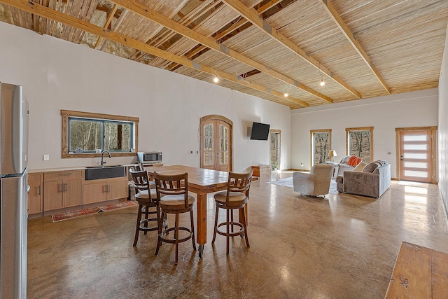 dining room featuring concrete flooring, french doors, and a towering ceiling