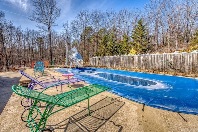 view of swimming pool with a patio area, a fenced backyard, a fenced in pool, and a water slide