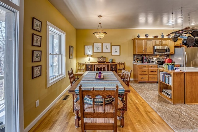 dining space featuring light wood-style floors, baseboards, and visible vents